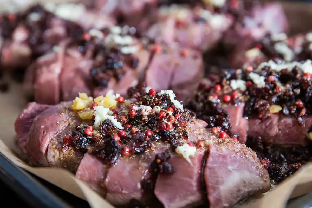 Tranches de viande ros&eacute;e, garnies d'une sauce fonc&eacute;e aux baies roses et d'ail &eacute;minc&eacute;. Un plat gastronomique fran&ccedil;ais pr&ecirc;t &agrave; &ecirc;tre d&eacute;gust&eacute;.