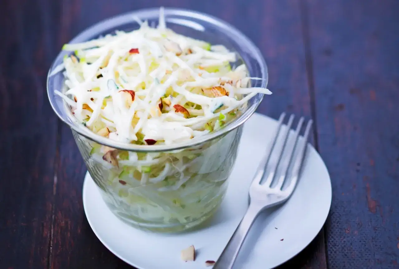 Salade croquante de céleri rave râpé, nappée d'une sauce crémeuse et parsemée de noix. Un délice frais et léger.