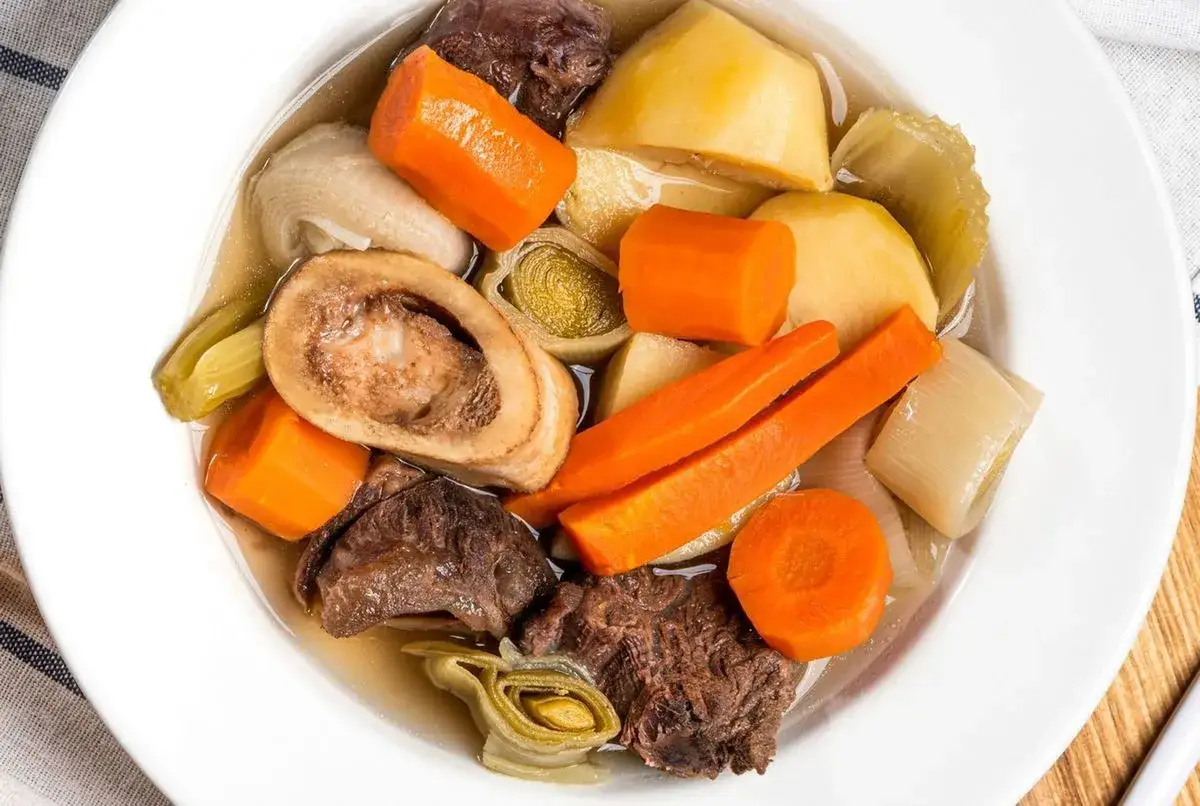 Un plat r&eacute;confortant de pot-au-feu, avec des morceaux de b&oelig;uf, des carottes, des pommes de terre et des poireaux, digne d'une recette du Journal des Femmes.