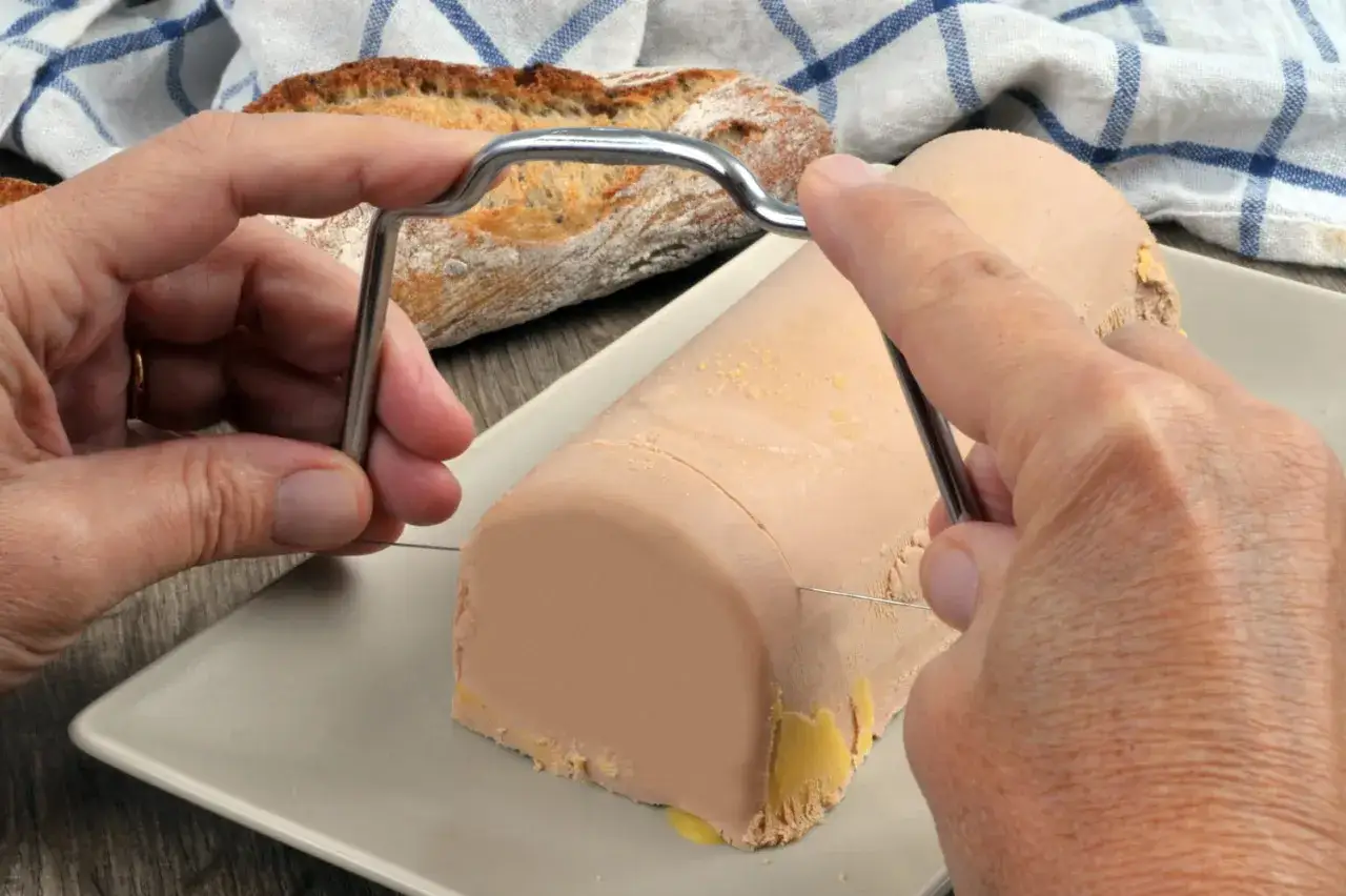 Comment couper le foie gras frais en tranches parfaites avec un fil. Un pain croustillant est prêt à être dégusté.