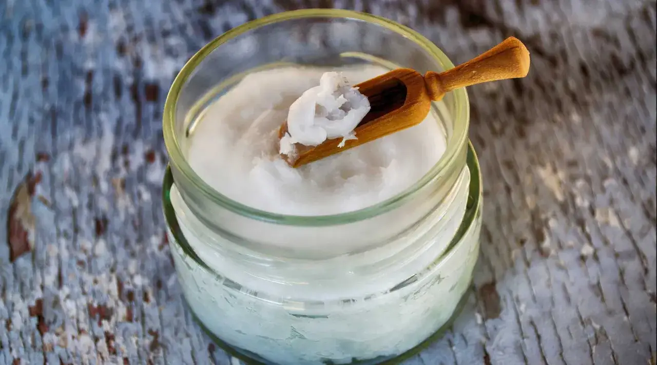 Un pot de noix de coco cr&eacute;meuse, parfaite pour la peau, avec une petite cuill&egrave;re en bois.