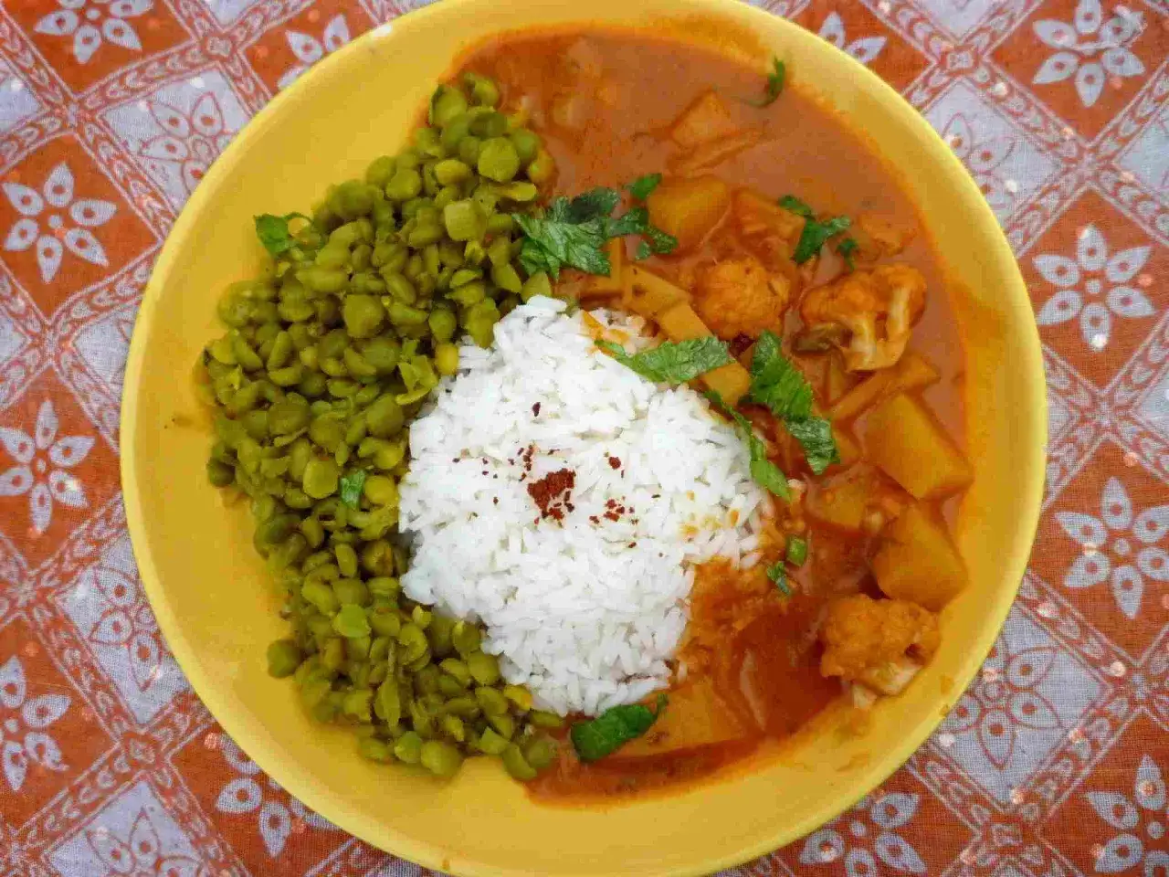 Un plat app&eacute;tissant de dahl de pois cass&eacute;s &agrave; l'indienne, servi avec du riz blanc et un curry de l&eacute;gumes sur une assiette jaune.