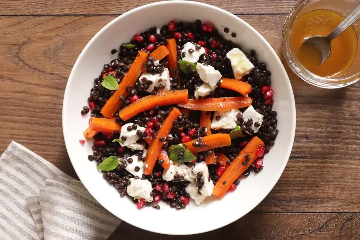 Salade colorée de lentilles beluga, carottes rôties, feta et grenade. Une recette facile et savoureuse.