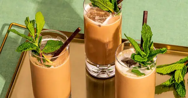 Trois mocktails rafraîchissants à la menthe et au chocolat, servis dans des verres hauts avec de la glace et des pailles foncées.
