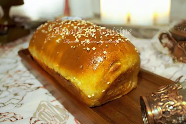 Un pain brioché salé doré, parsemé de graines, sur un plateau en bois. Parfait pour une recette facile et savoureuse.