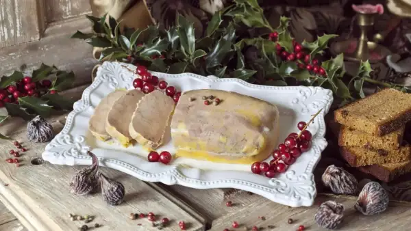 Un foie gras prêt à être dégusté pour Noël, accompagné de pain d'épices et de fruits secs. La question "quand faire le foie gras pour Noël" est résolue avec cette belle présentation.