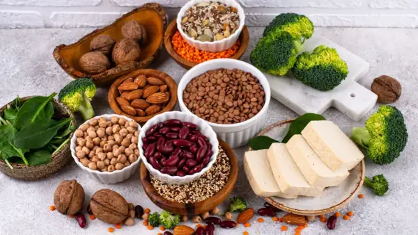 Un assortiment de protéines végétales : haricots rouges, lentilles, pois chiches, amandes, noix, tofu, brocolis et épinards. Le haricot rouge bienfait est un allié santé.